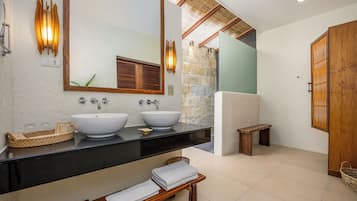 Un baño moderno con dos lavamanos, un espejo grande y un banco de madera.