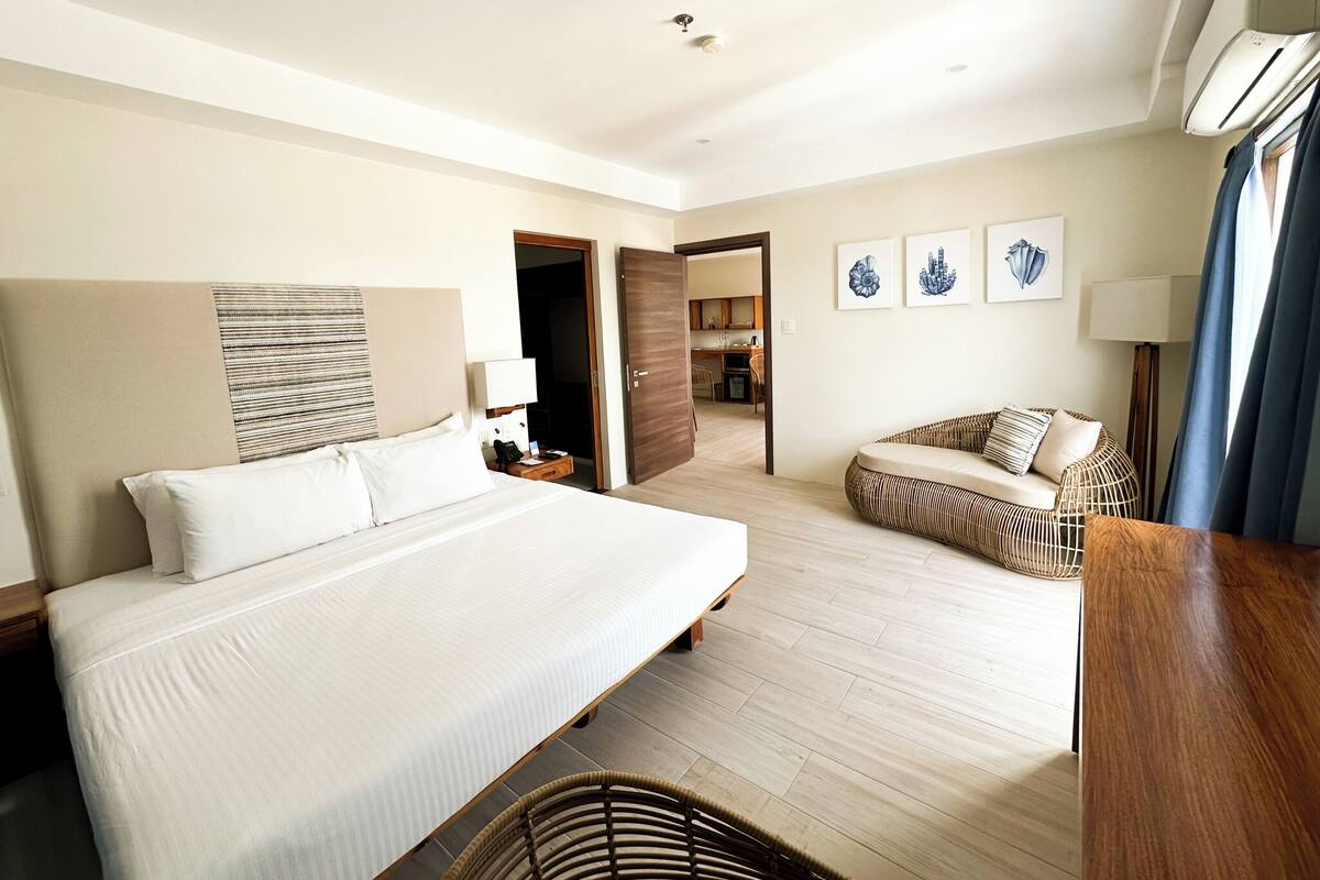 Ein Hotelzimmer mit einem großen Bett, einer Sitzecke, einem Essbereich und Blick auf die Stadt.