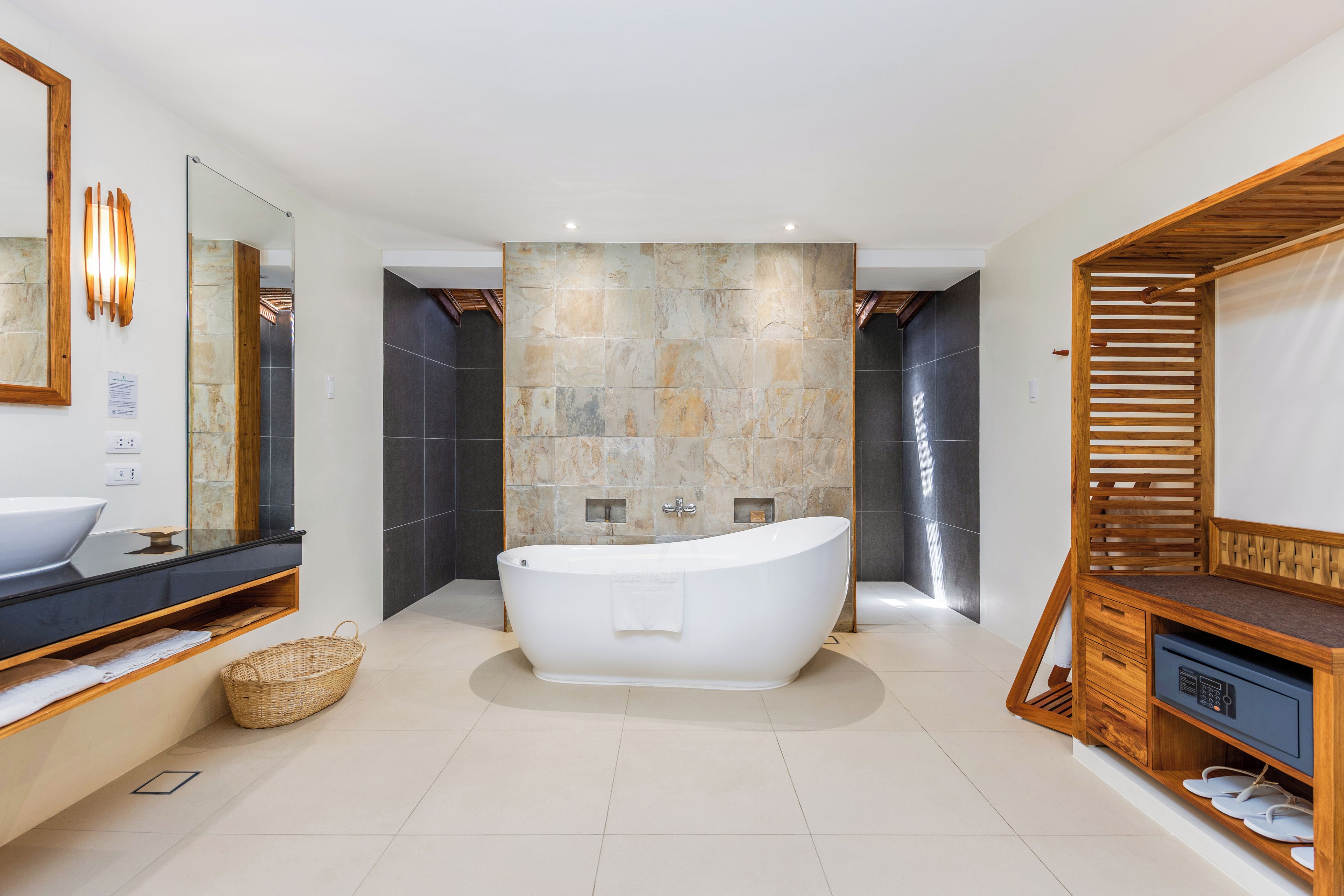 A modern bathroom with a freestanding bathtub, a large mirror, and a wooden vanity.