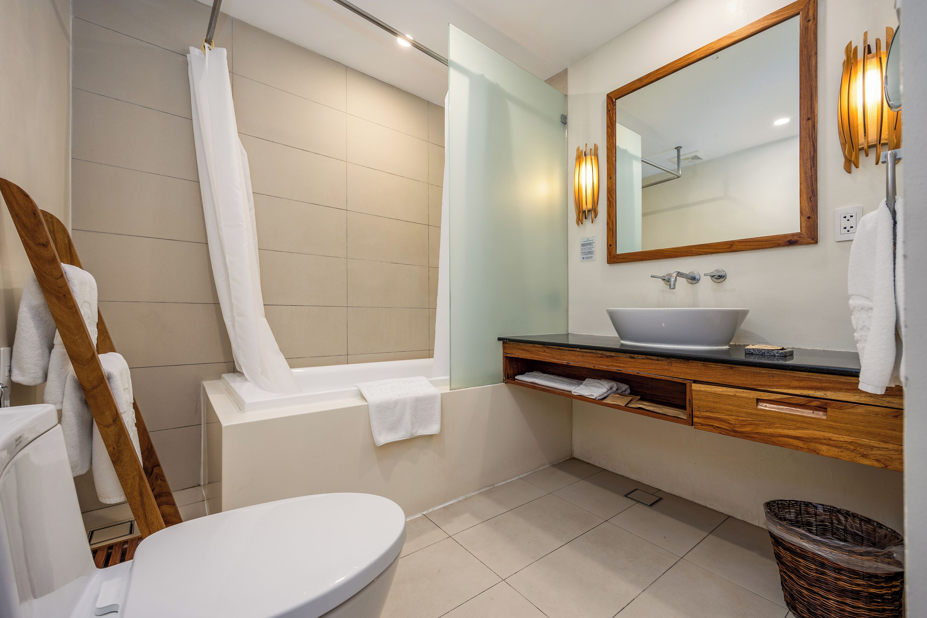 Un baño moderno con bañera, lavamanos con espejo e inodoro.