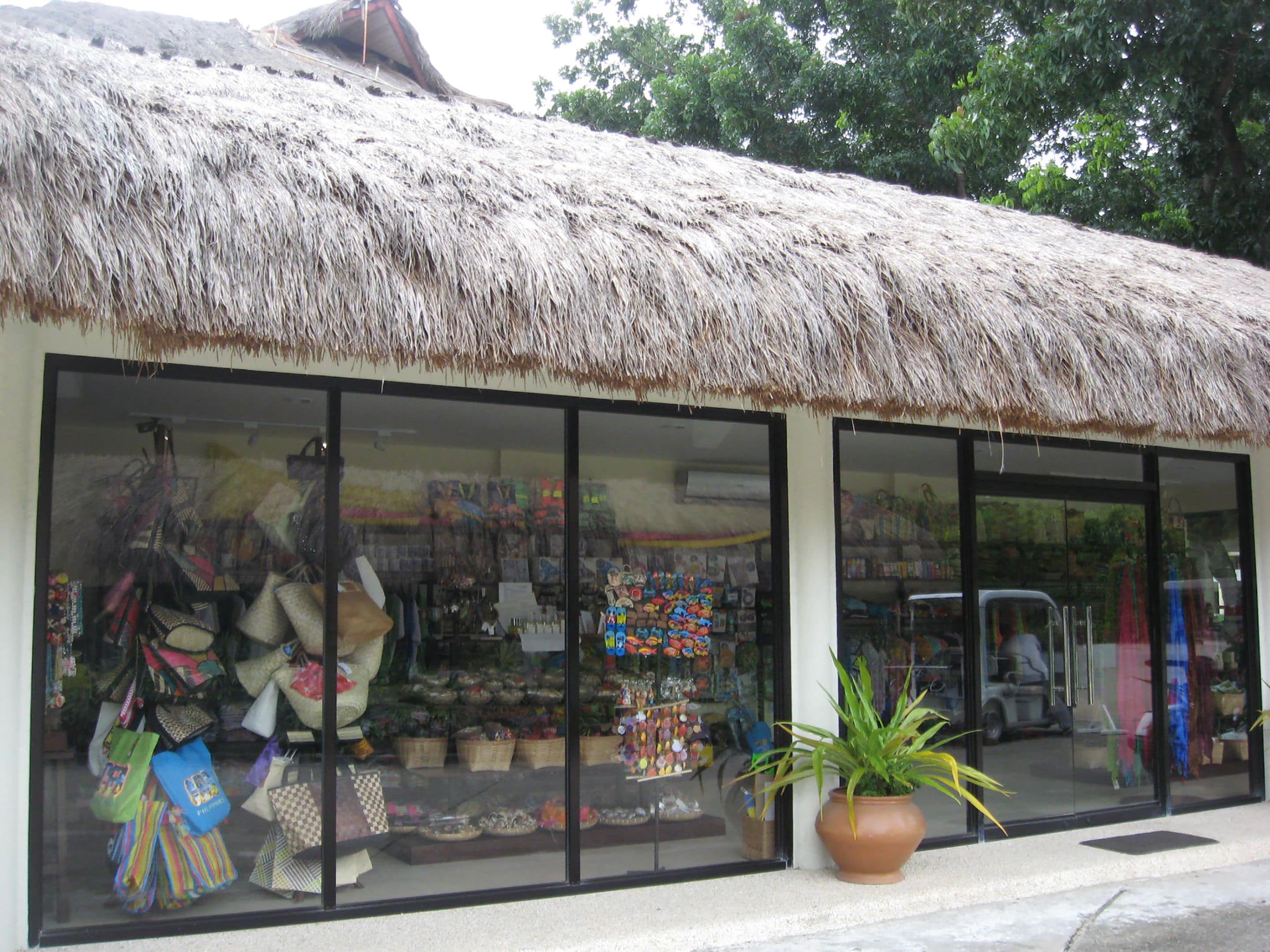 Una tienda con techo de paja y amplios ventanales que exhiben diversos artículos.