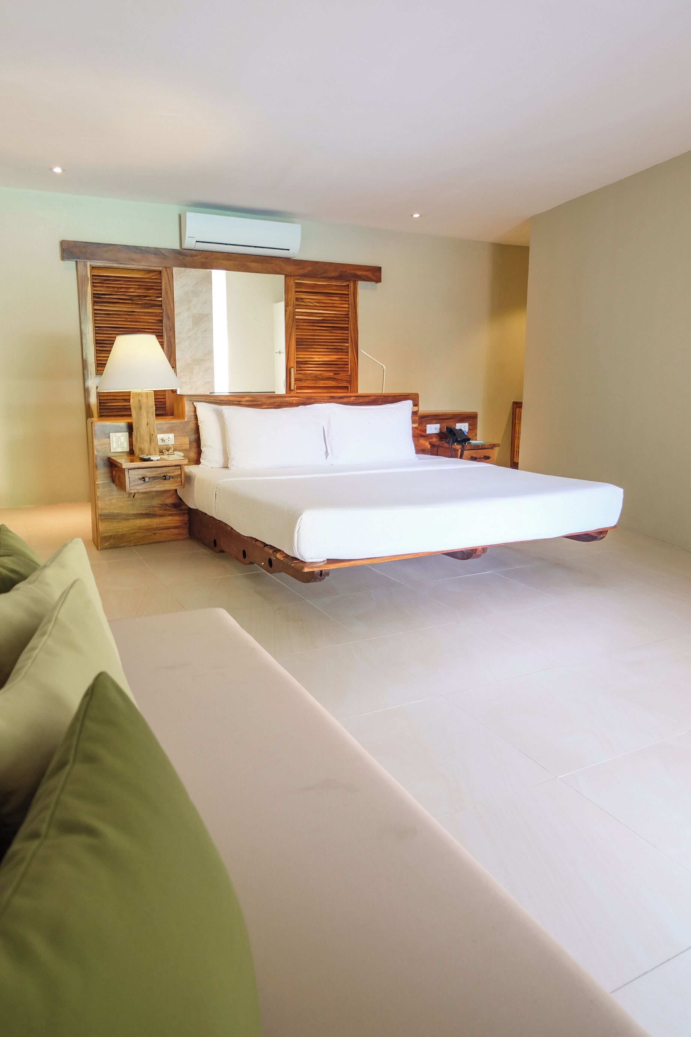 A spacious bedroom with a large bed, a bedside table with a lamp, and a wooden headboard.