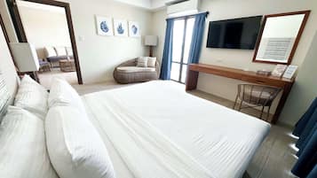 Habitación de hotel con una cama grande, un escritorio, una silla, un televisor y una ventana con cortinas.