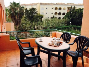 A balcony with a table set for two, chairs, and a tray with a teapot and cups. - Marbella Beach Resort at Club Playa Real (Marbella)