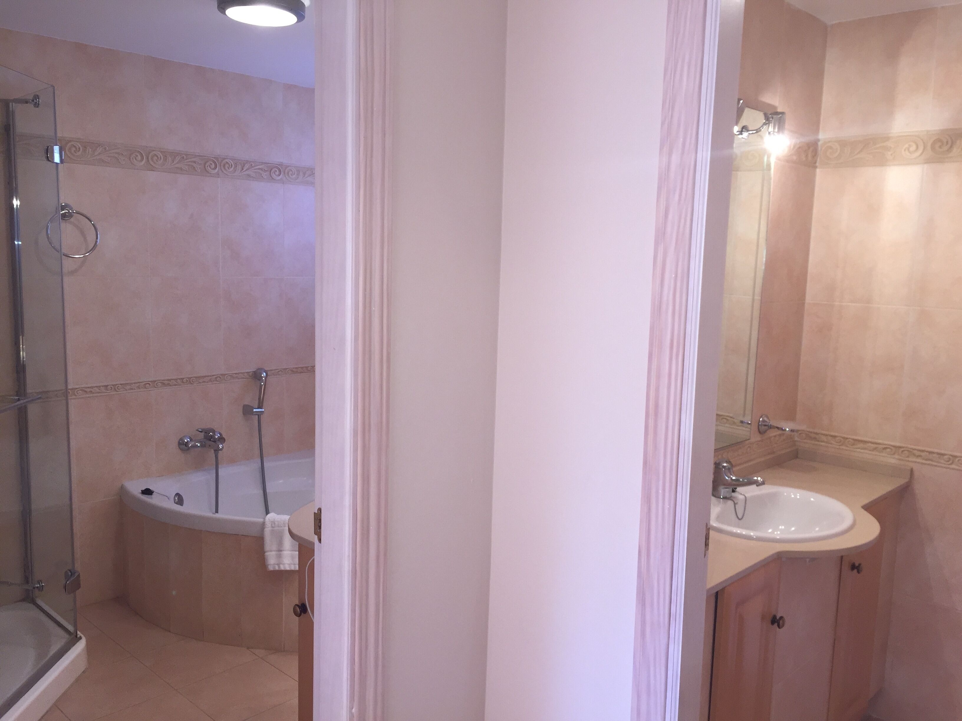 A bathroom with a glass shower enclosure, a bathtub, and a sink with a mirror.