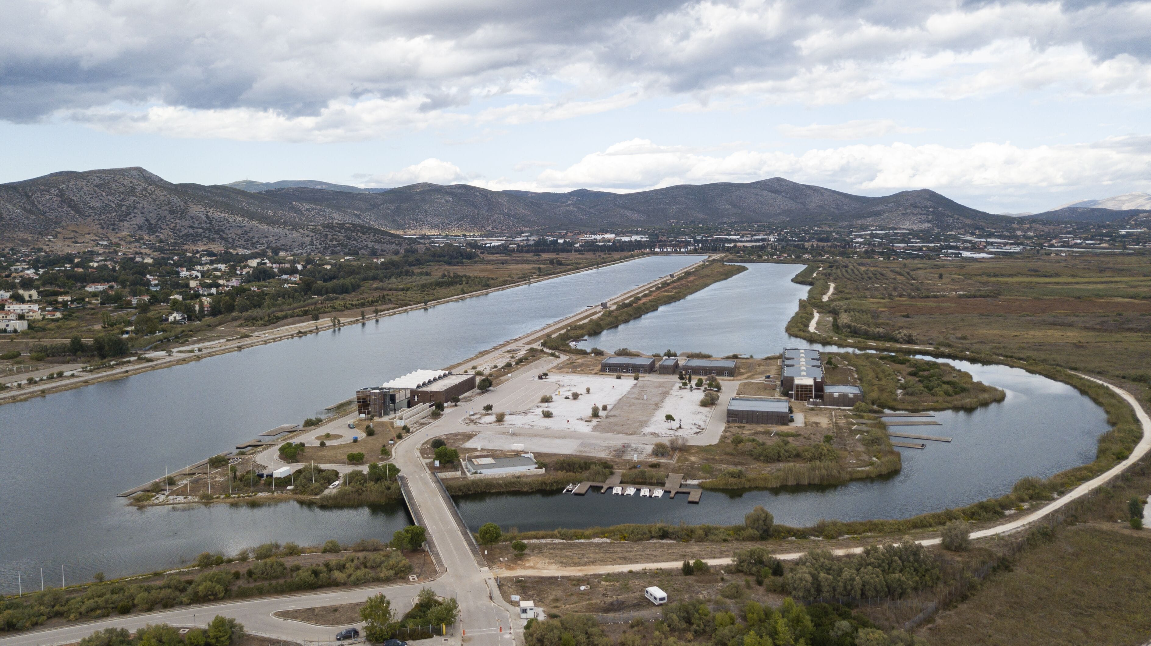 A river with a bridge, a parking lot, and industrial buildings.
