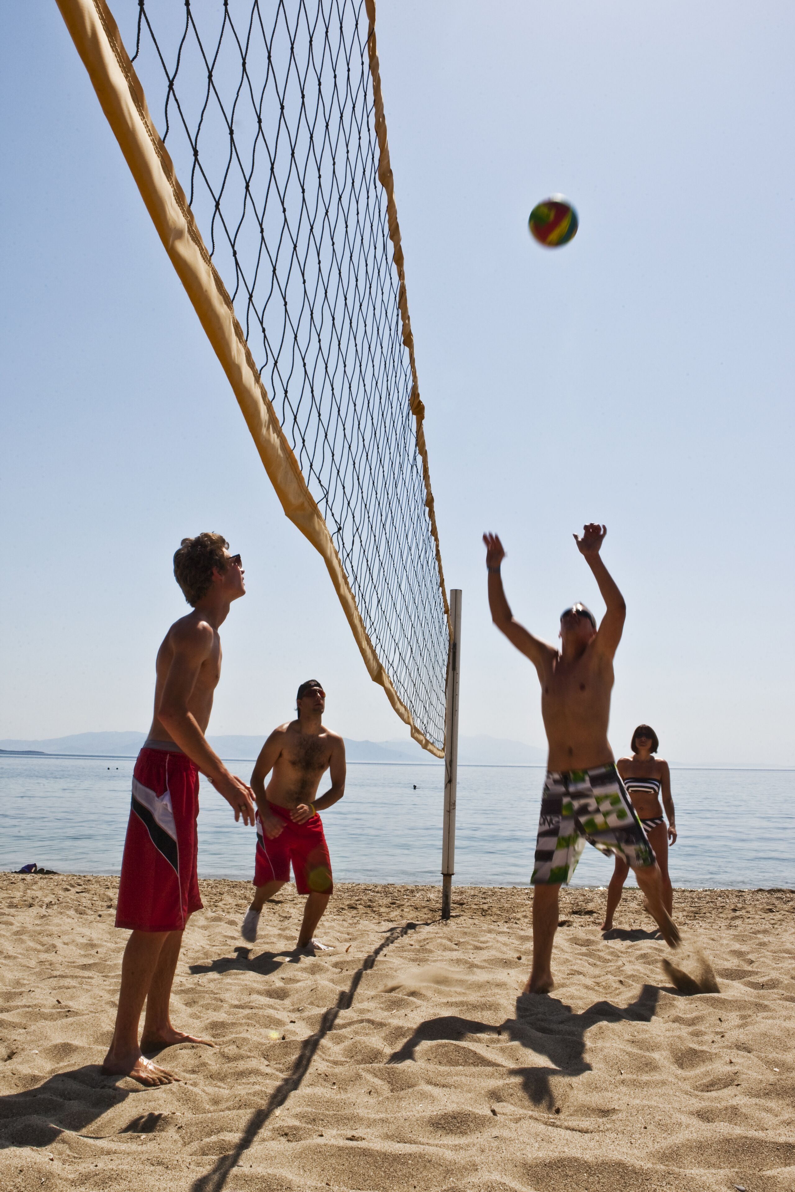 A beach volleyball game with players and a net.
