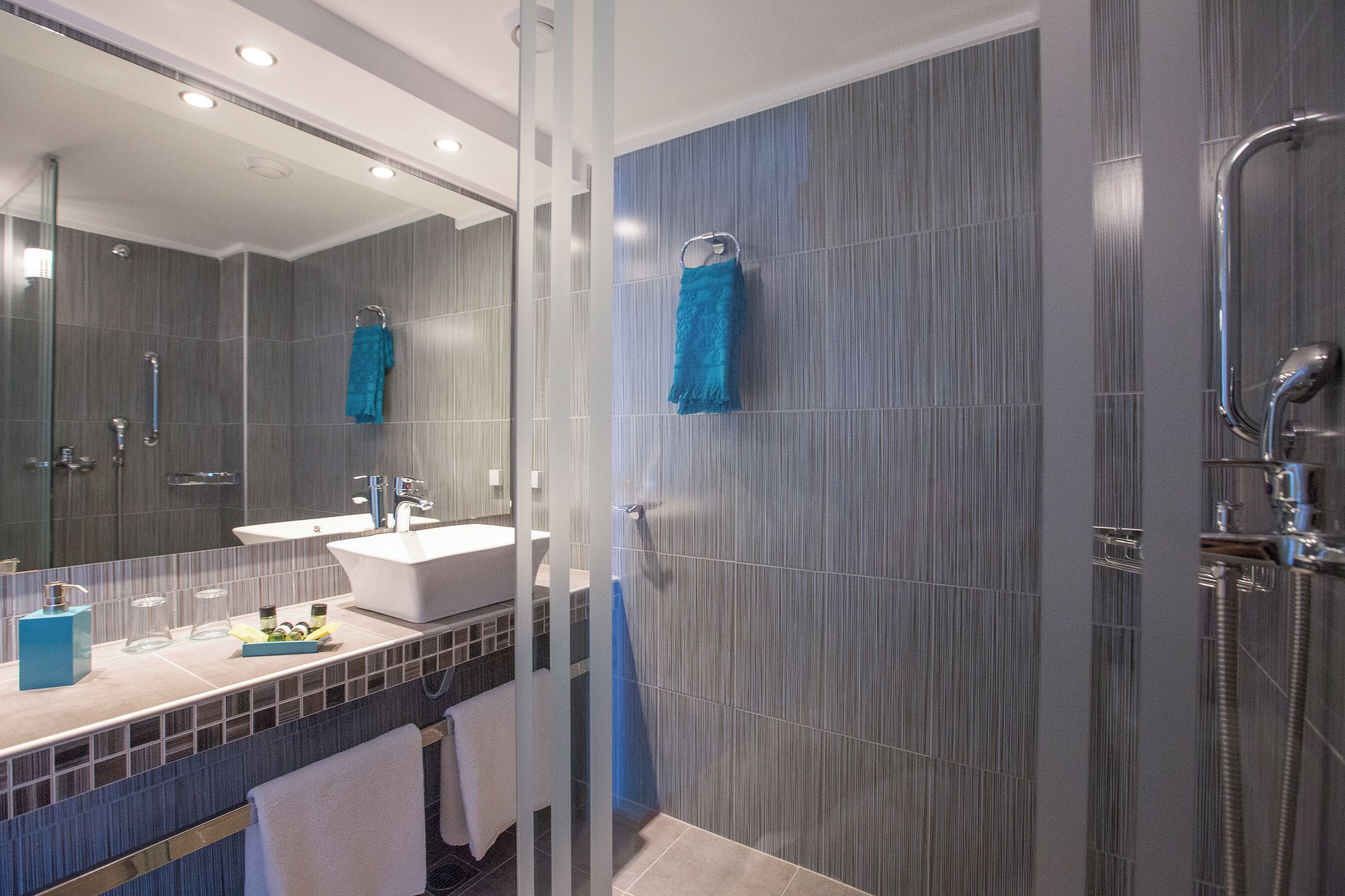 A modern bathroom with a glass shower enclosure, a sink, and a mirror.
