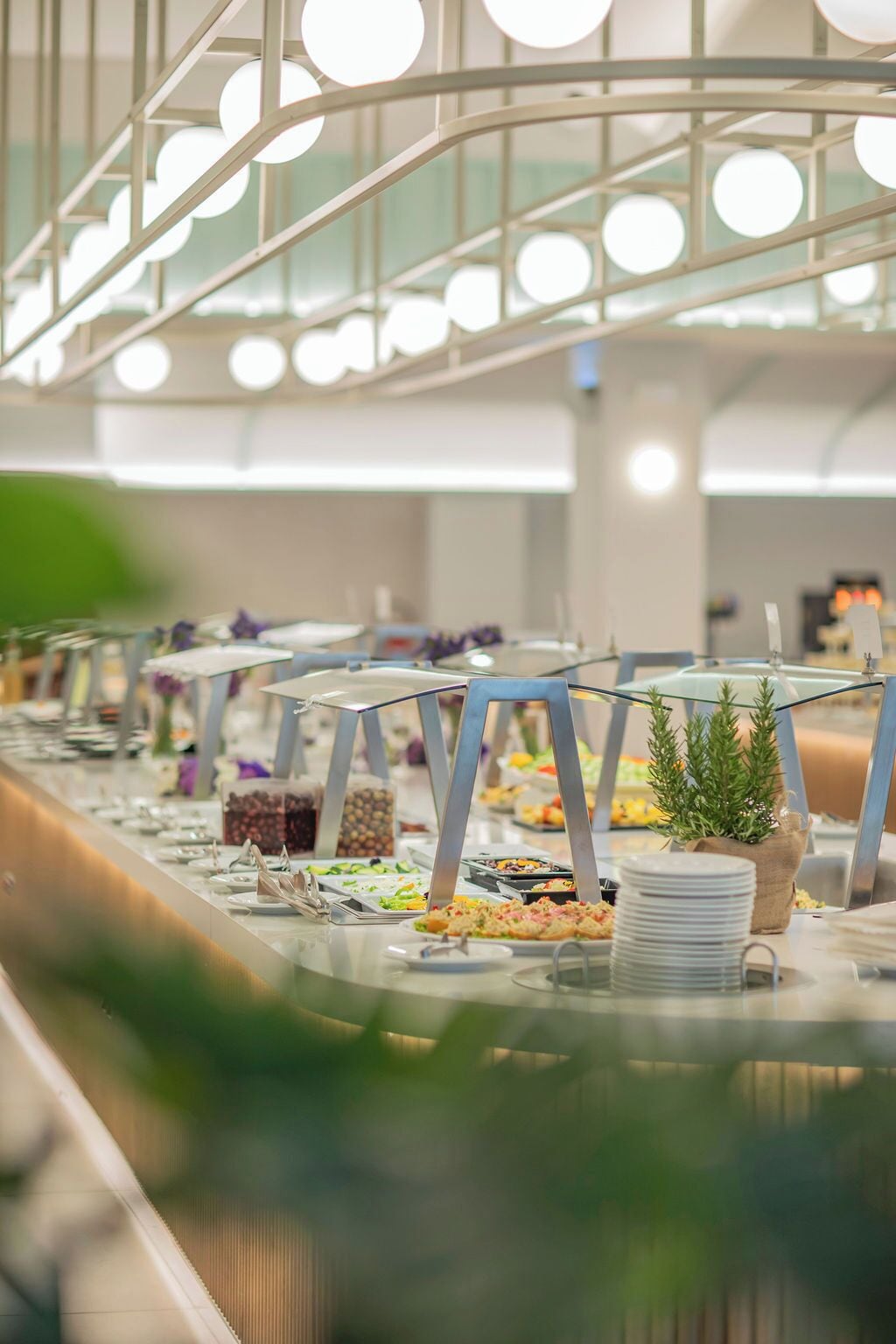 A buffet setup with various food stations, a glass railing, and a modern interior design.