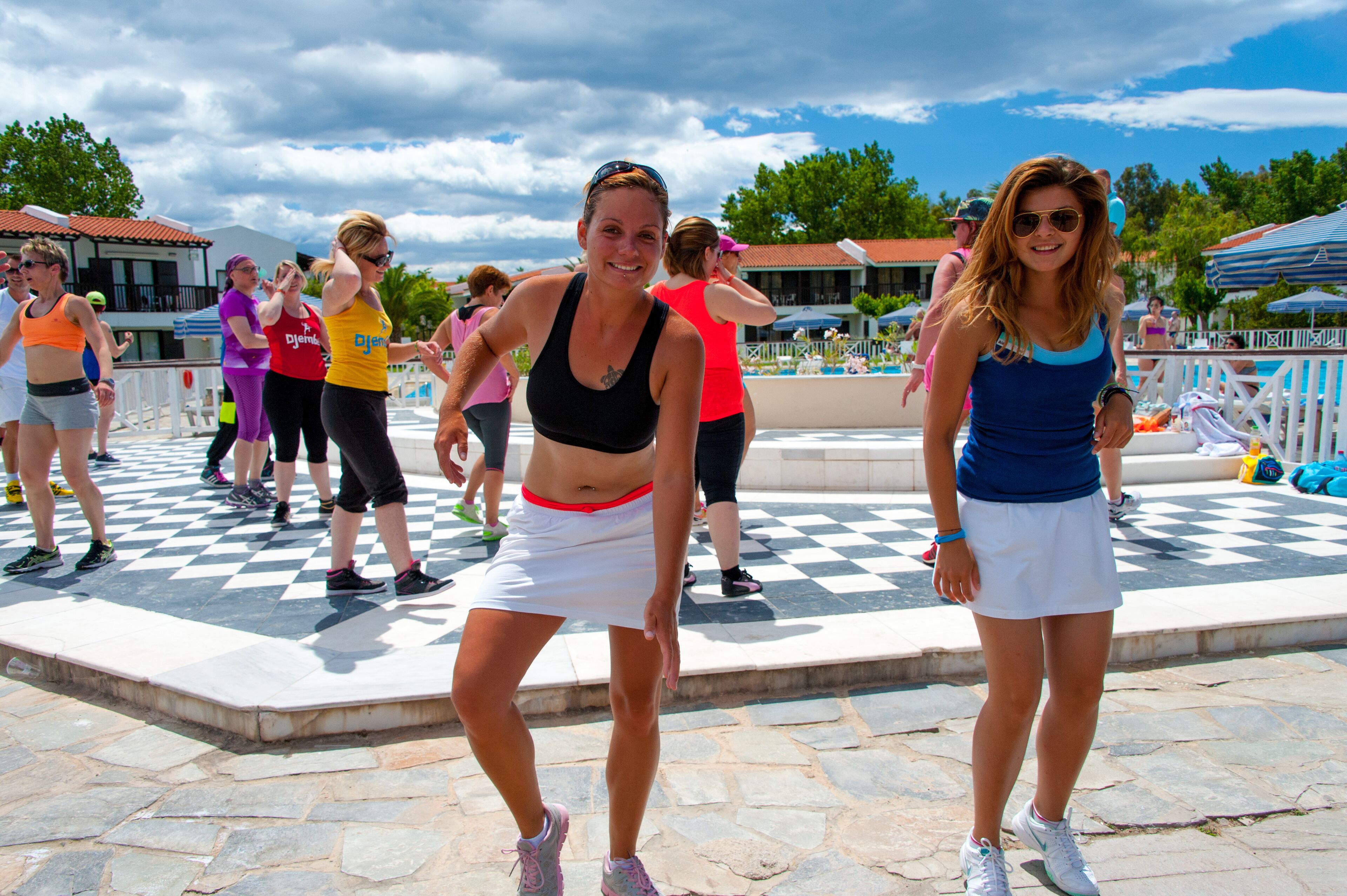 A group of people exercising outdoors on a checkered pavement.