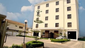 Un hotel a più piani con facciata lineare, numerose finestre e un'area di parcheggio antistante.