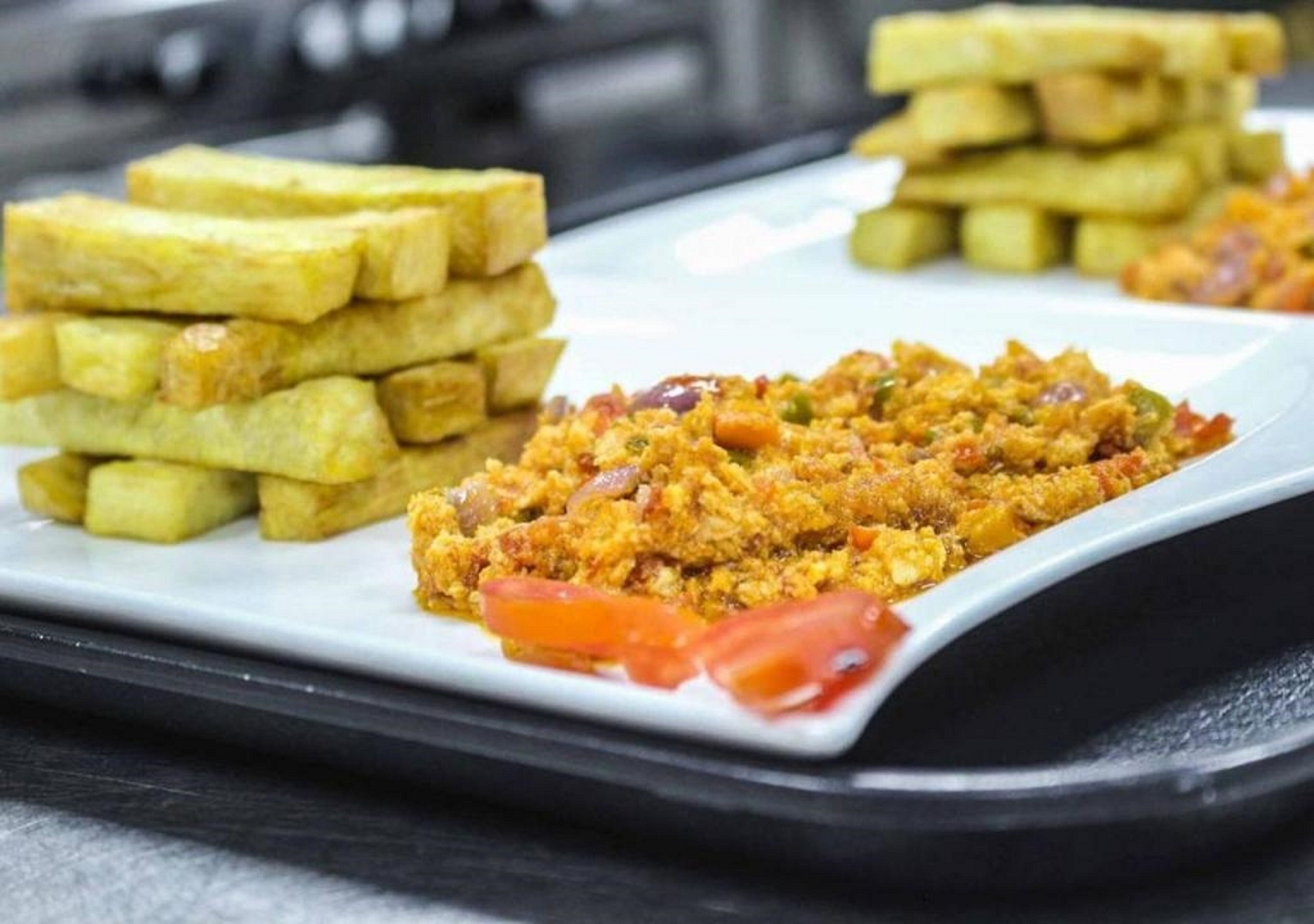 A plate with scrambled eggs, French toast, and tomato slices.