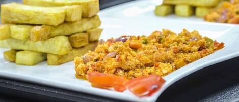 A plate with scrambled eggs, French toast, and tomato slices.