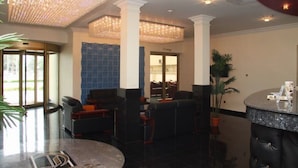 Una hall con un lampadario, zona salotto e reception.