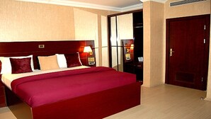 Una camera d'albergo con un letto grande, comodini, un armadio e una porta.