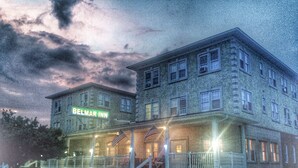 Un edificio de dos pisos con un letrero que dice "BELMAR INN" en la entrada.