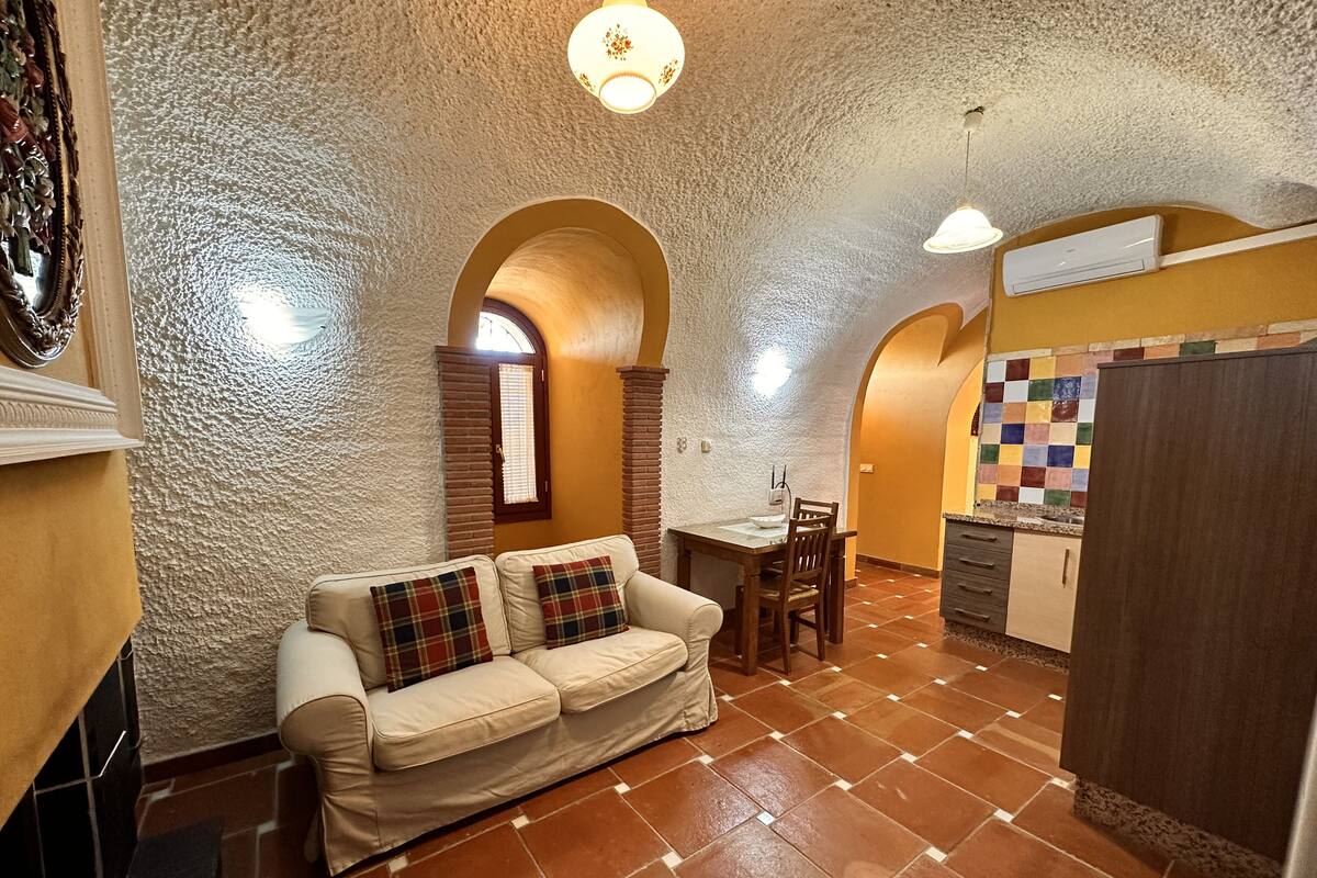A cozy living area with a sofa, a dining table, and a kitchen area with a tiled backsplash.