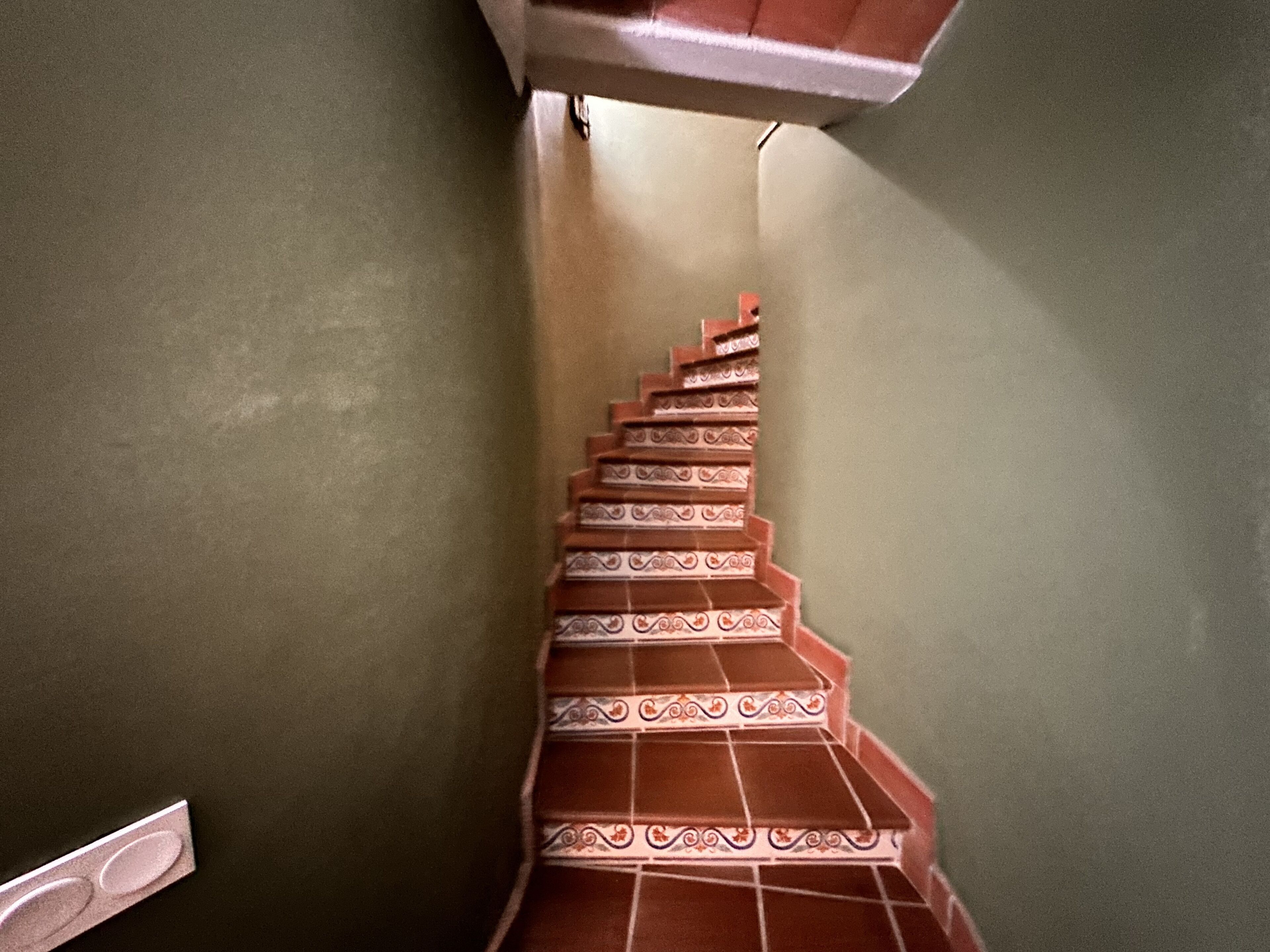A staircase with ornate red and white tiles leading to a landing.