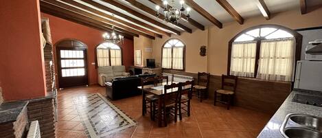 A spacious kitchen with a dining area, a fireplace, and a large window.