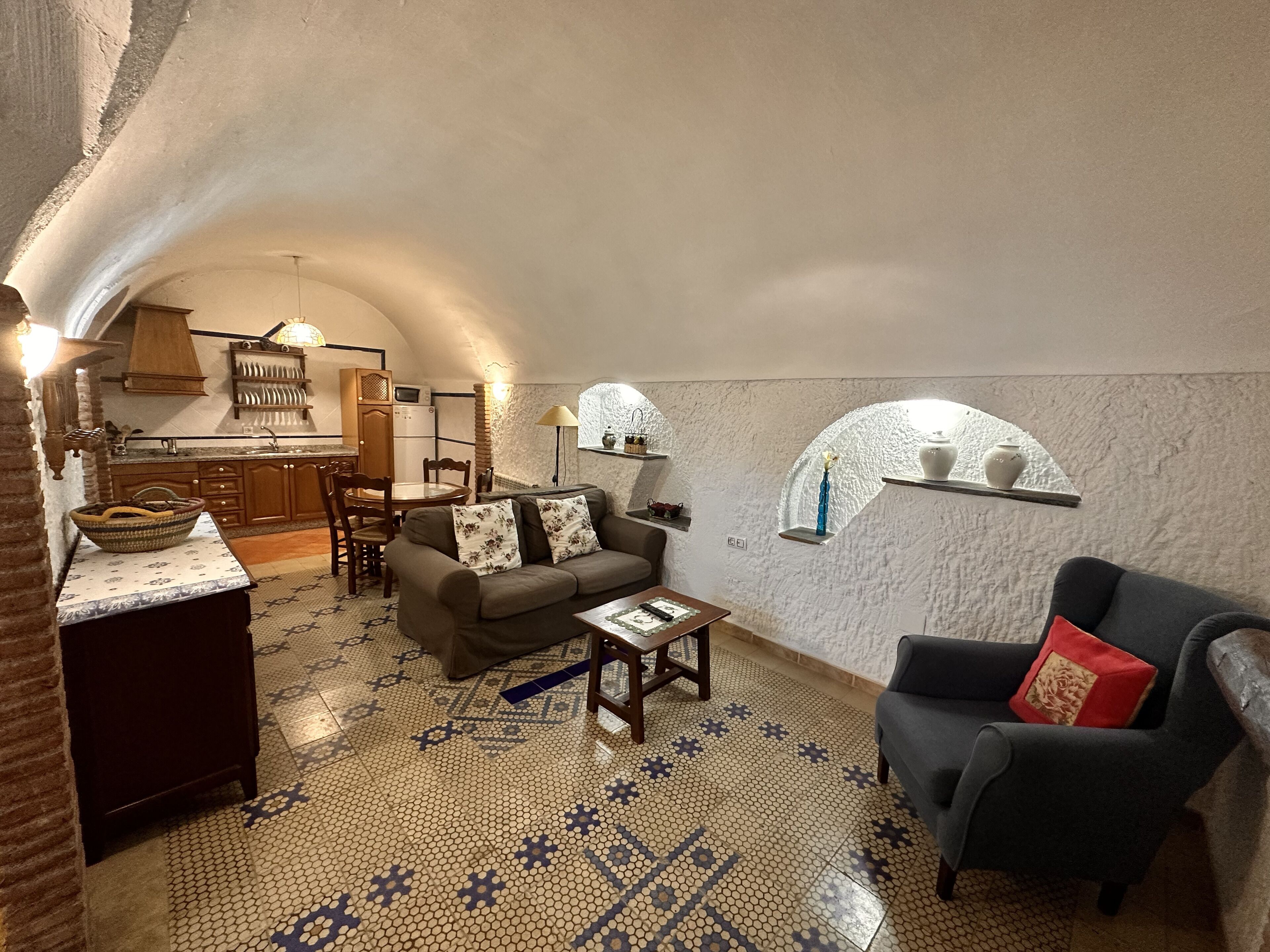 Un espacio de sala acogedor y parcialmente abierto, con área de cocina, sofá y mesa de comedor.