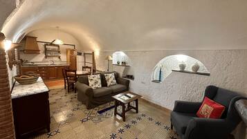 Un espacio de sala acogedor y parcialmente abierto, con área de cocina, sofá y mesa de comedor.