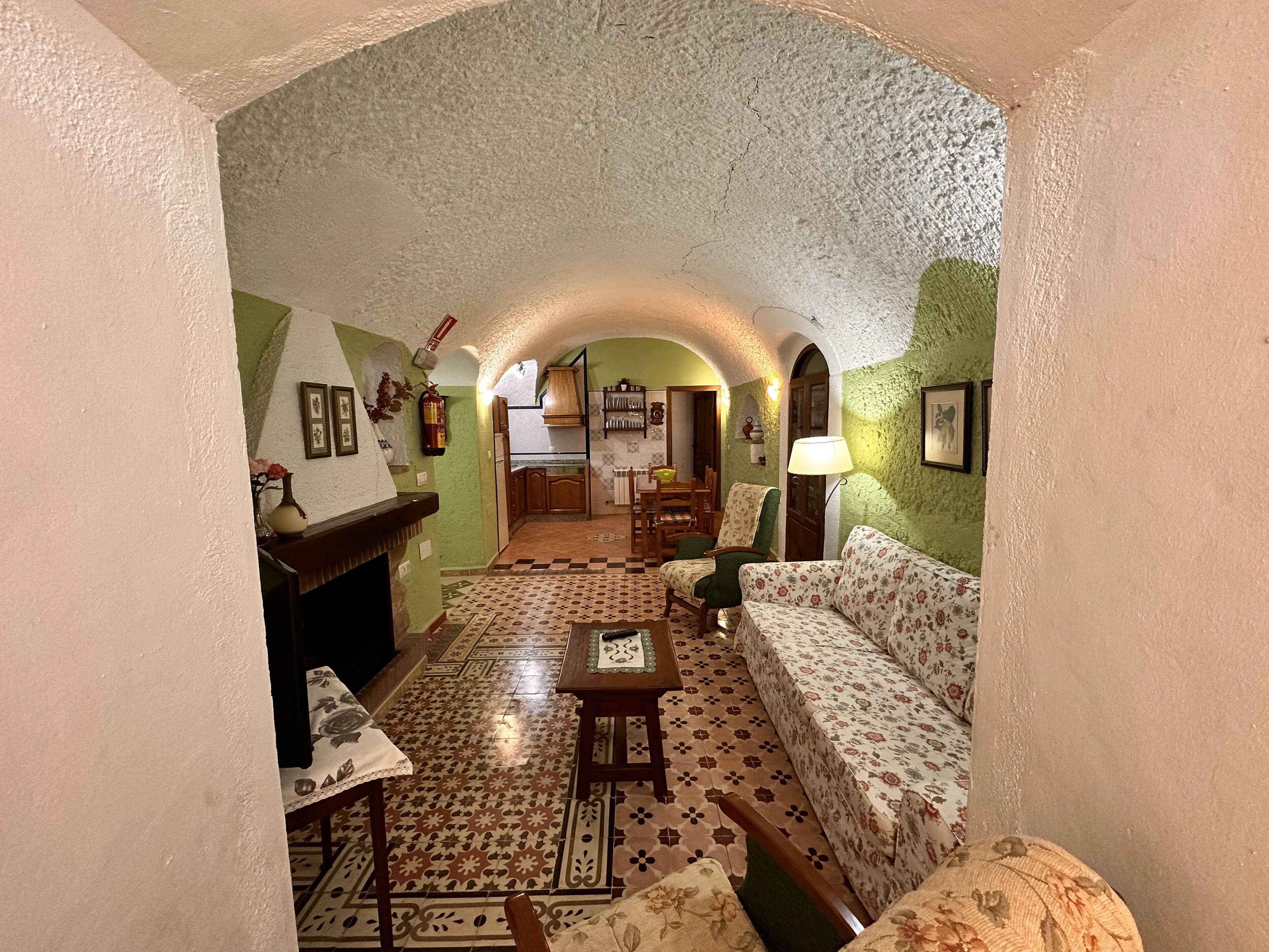 Una sala de estar acogedora con suelo estampado, un sofá, una mesa y una chimenea.