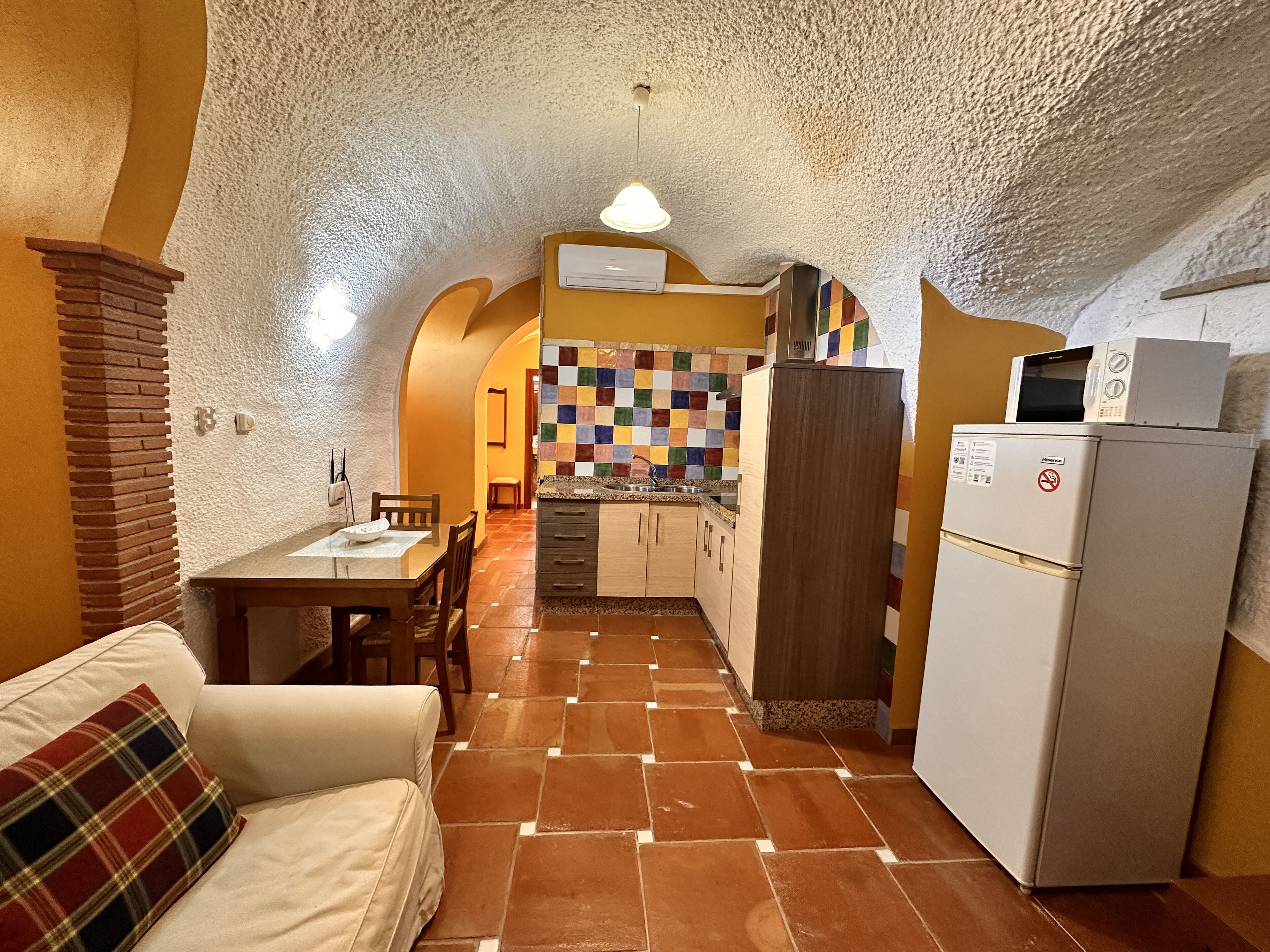 A compact kitchen with a tiled backsplash, a refrigerator, and a microwave.