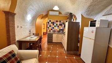 A compact kitchen with a tiled backsplash, a refrigerator, and a microwave.