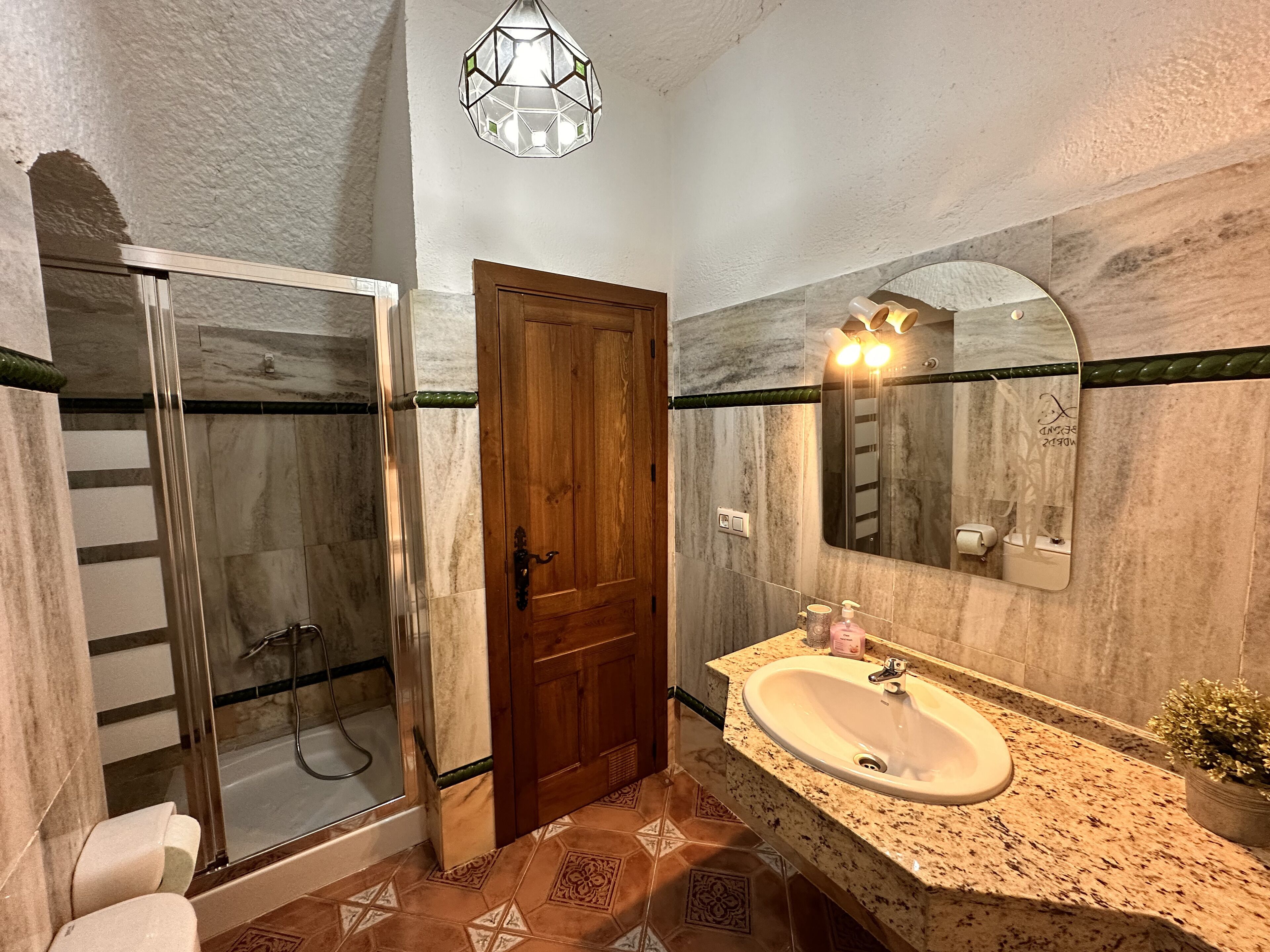 Un baño con ducha, lavabo, espejo y puerta.