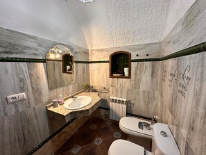 Un baño con lavamanos de mármol, espejo, toallero y inodoro.