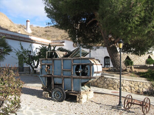 A vintage cart with wheels, a lamp post, and a stone wall in the background. - Cuevas la Granja (Benalua de Guadix)