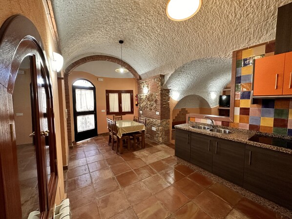 A kitchen with a tiled floor, a dining area with a table and chairs, and a colorful backsplash.