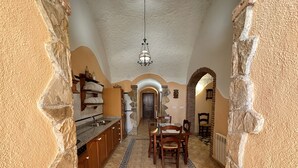 Una cocina con una isla central, armarios de madera, un arco de piedra y suelo de baldosas.