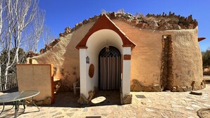 Un edificio rústico con fachada de piedra, patio de baldosas y una reja de metal.