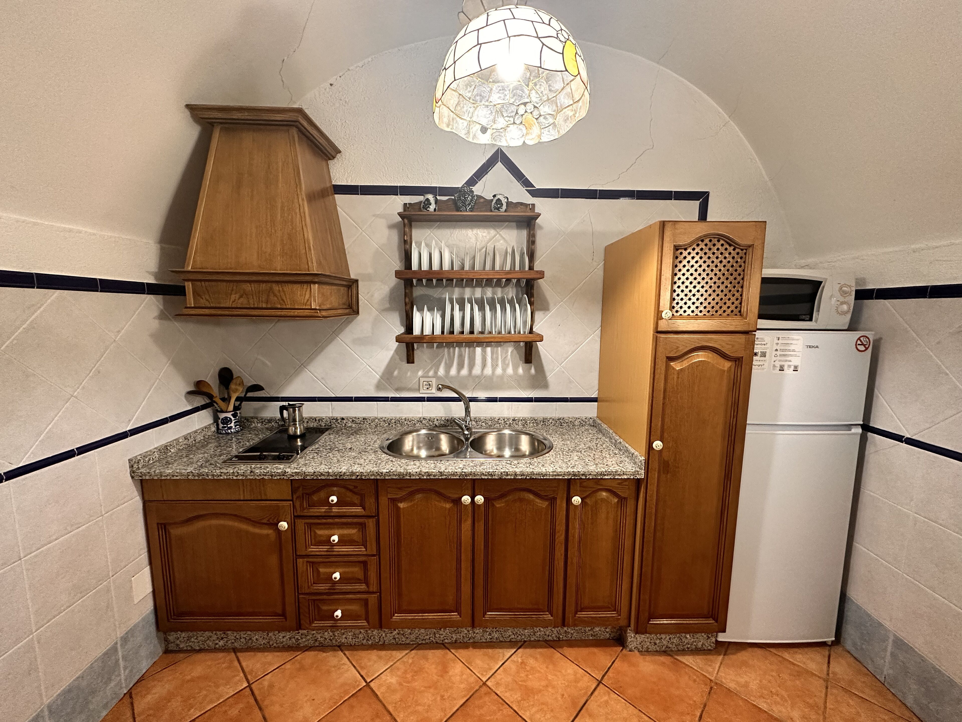 Une cuisine avec des meubles de rangement en bois, un évier à deux bacs, un four à micro-ondes et un réfrigérateur.