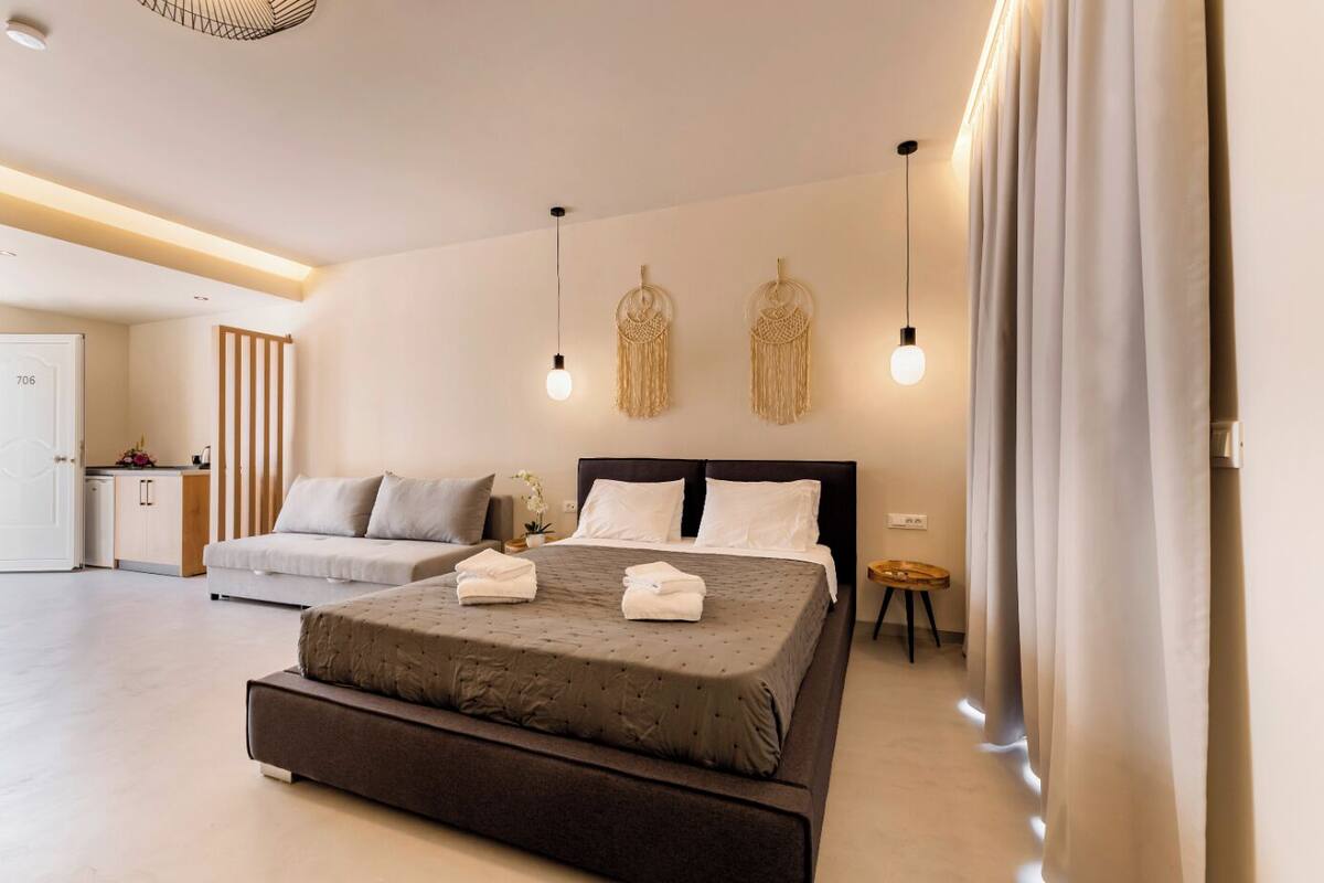 A modern bedroom with a large bed, a sofa, and a small table.