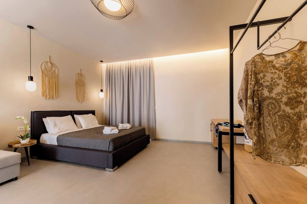 A modern bedroom with a bed, bedside tables, a hanging light fixture, and a wardrobe.