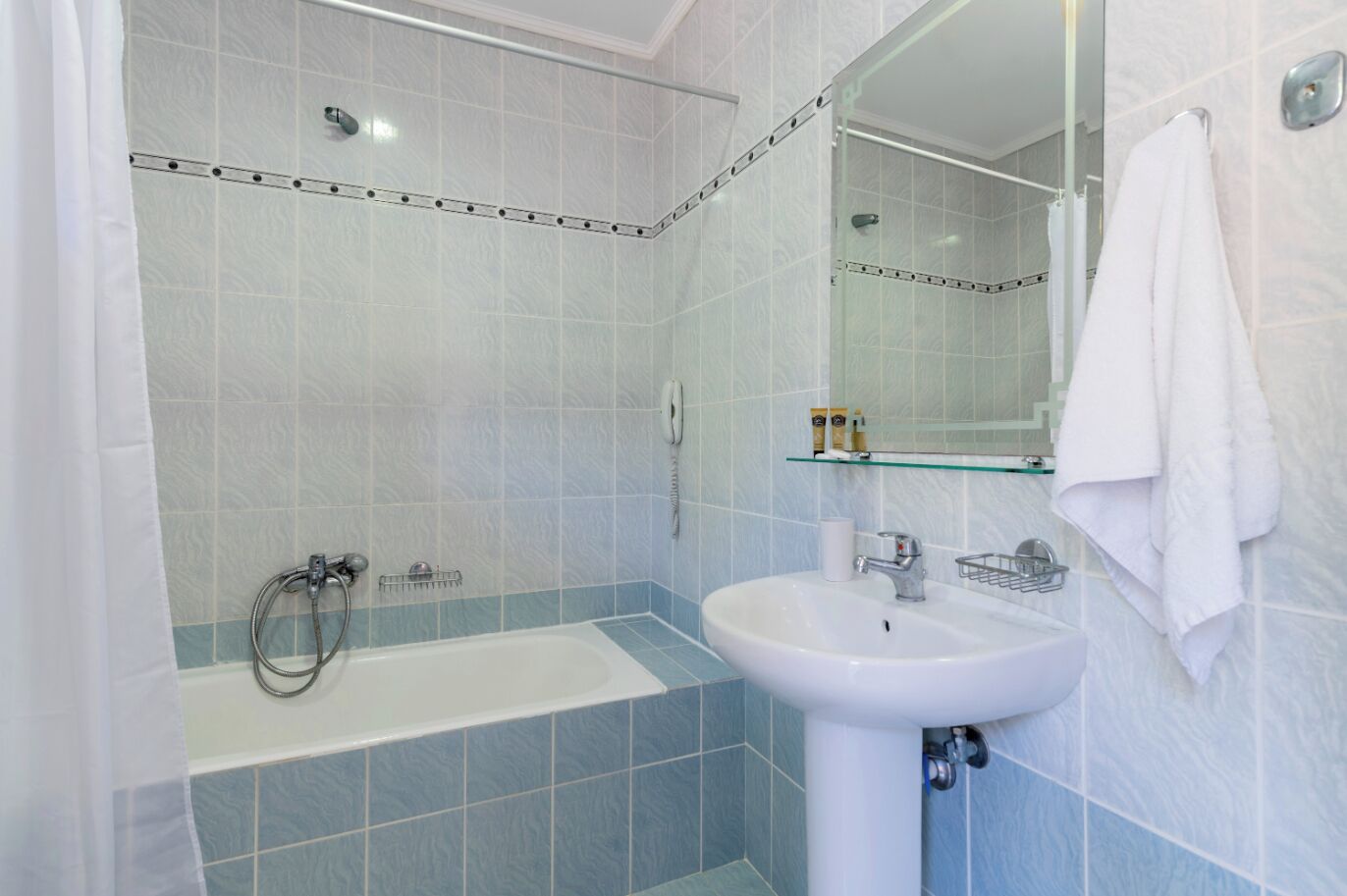 A bathroom with a bathtub, a sink, and a glass shower enclosure.