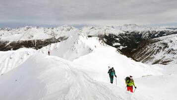 Paisaje nevado de montañas con dos excursionistas.