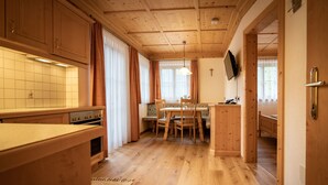 Un interior de madera con cocina, comedor y un pasillo que lleva a un dormitorio.
