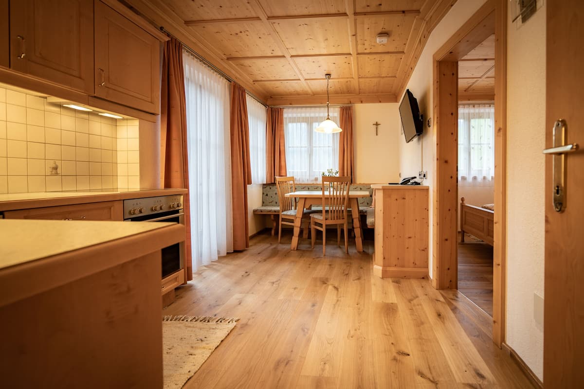 A wooden interior with a kitchen, dining area, and a hallway leading to a bedroom.