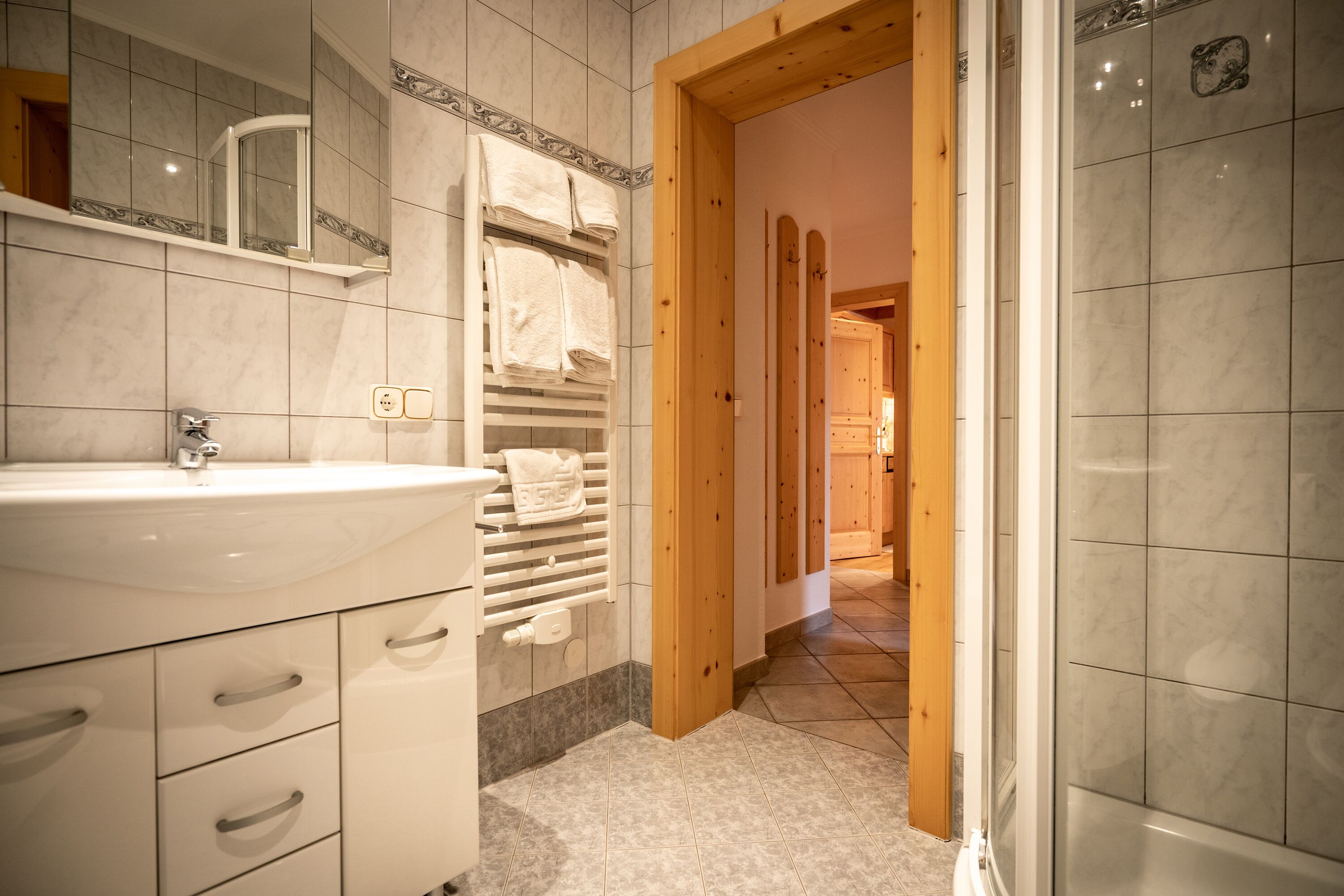 A bathroom with a white sink, towel rack, and wooden doorways leading to other rooms.