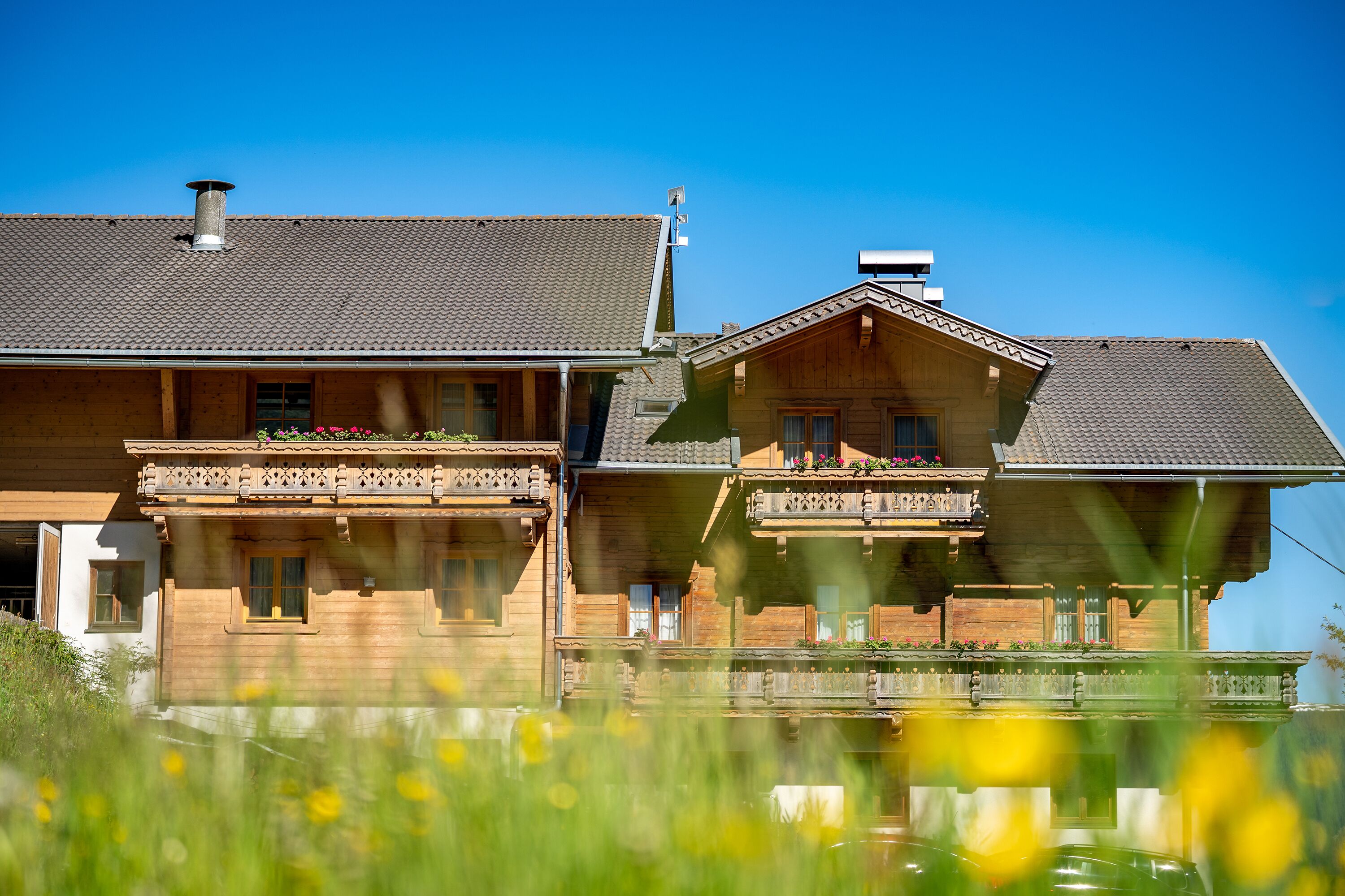 A wooden house with a balcony and a small pond in front.