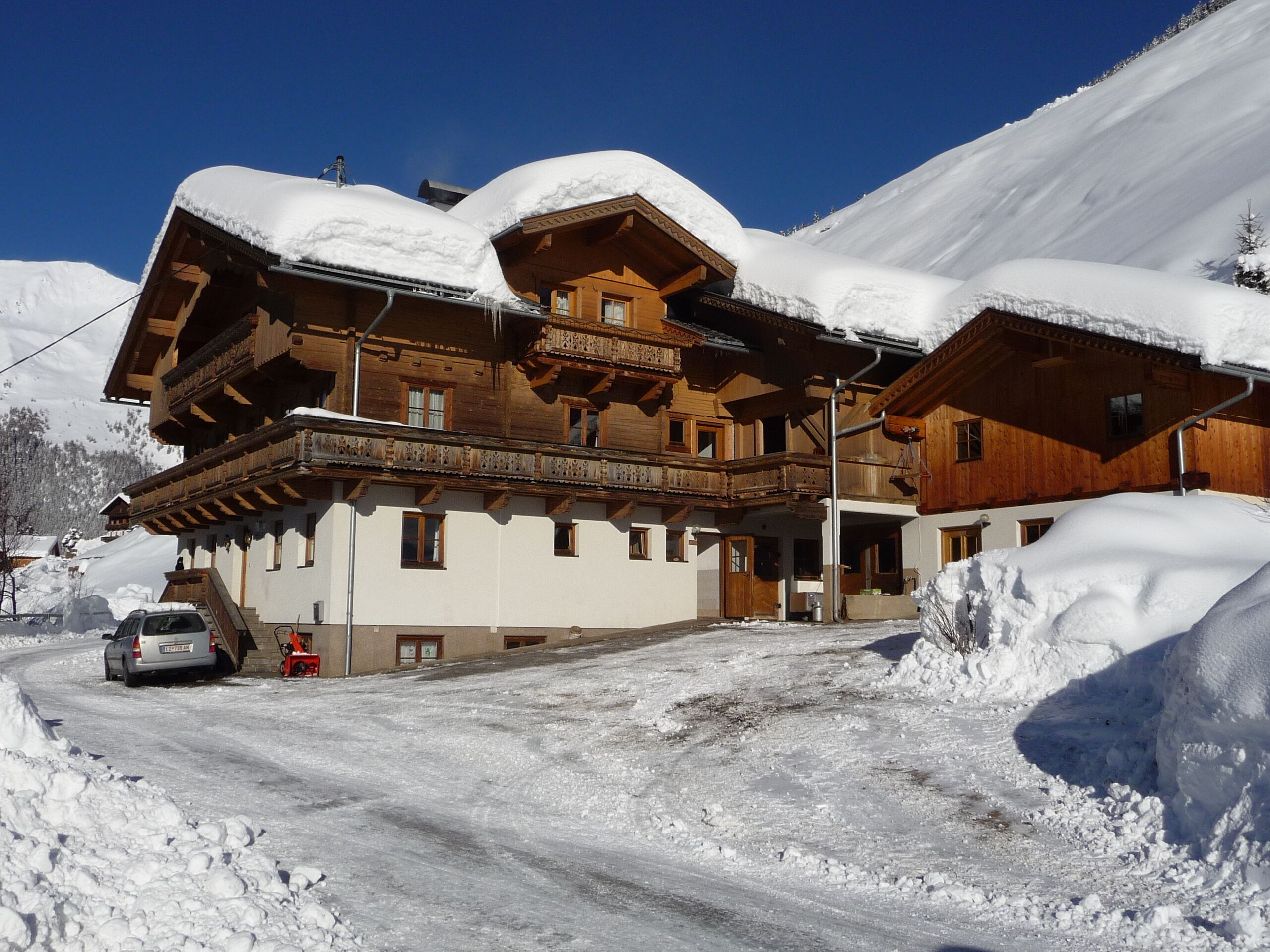 Un chalet en bois doté d’un balcon, entouré de montagnes enneigées.
