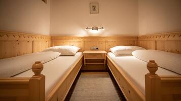Ein Zimmer mit zwei Holzbett, einem kleinen Nachttisch und einer Wandleuchte.