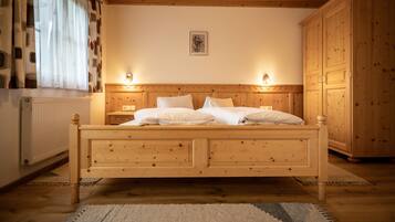 A wooden bed with two bedside tables, a radiator, and a wardrobe in a room with wooden walls and ceiling.