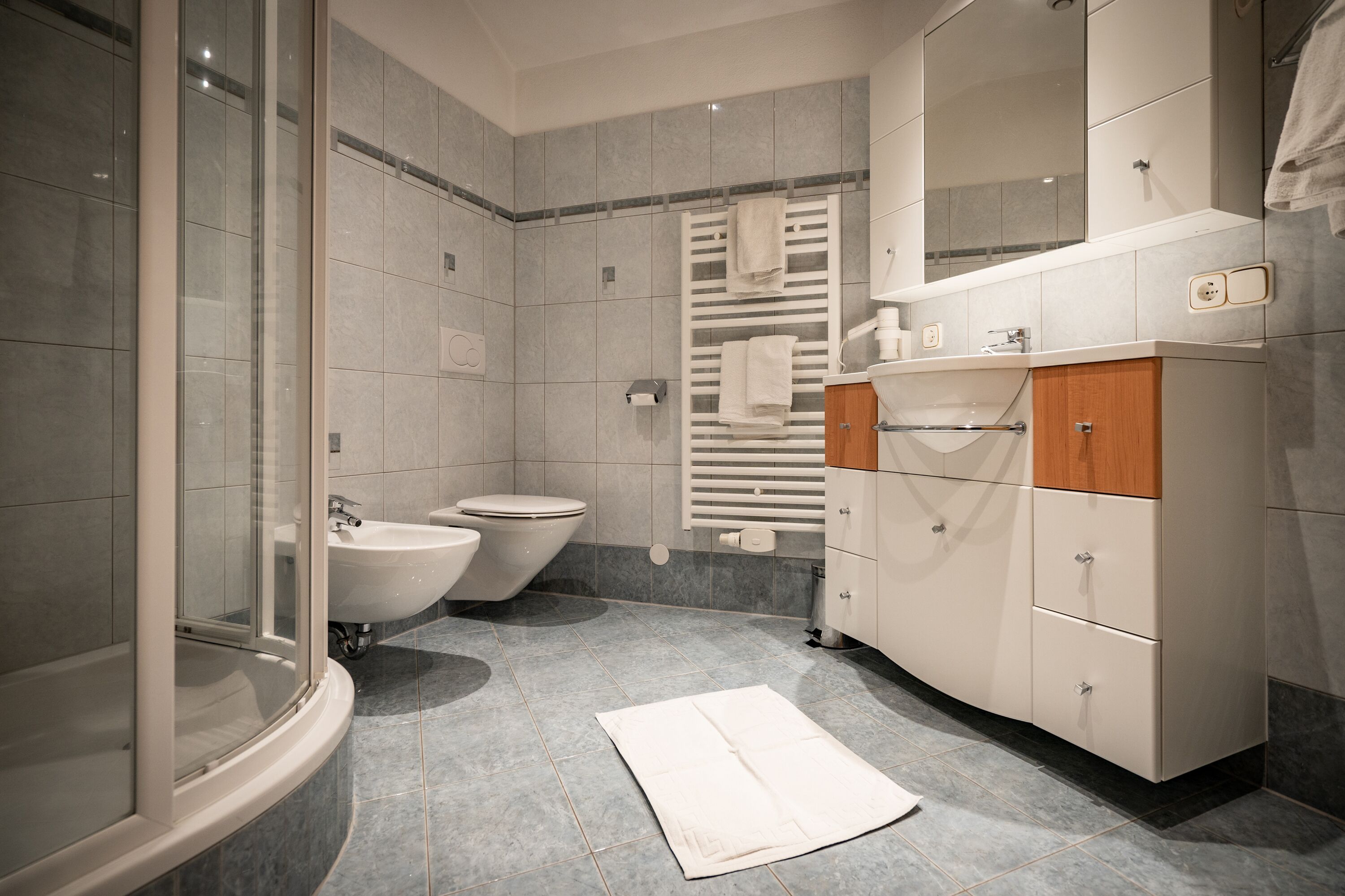 Un baño moderno con cabina de ducha de vidrio, lavabo blanco y un inodoro.