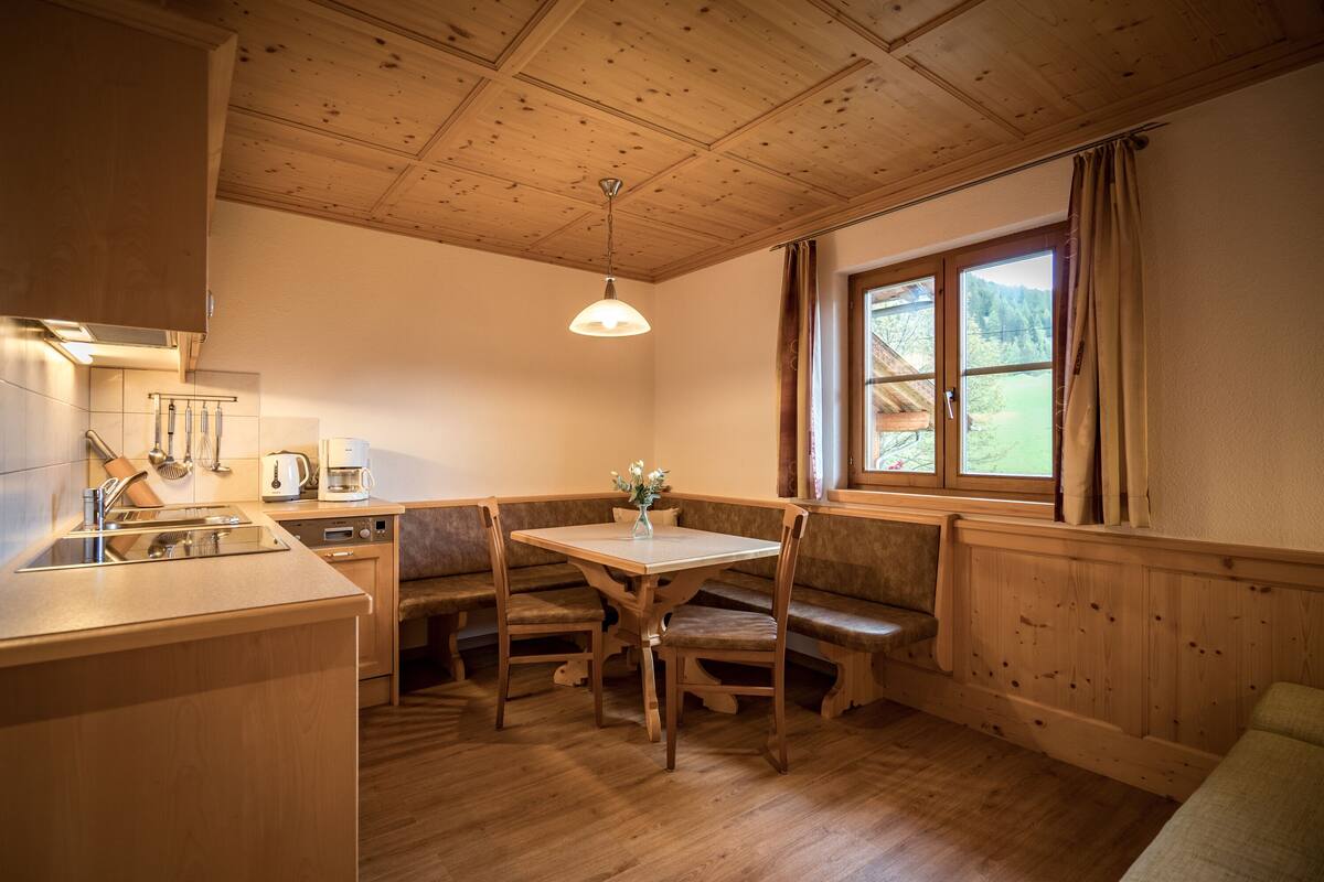 A cozy kitchen with wooden cabinets, a dining table, and a bench.