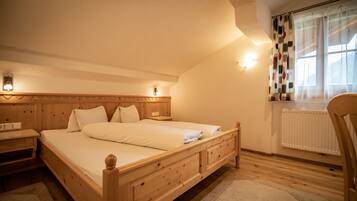 Une chambre à coucher avec un lit en bois, des tables de chevet, une fenêtre avec des rideaux et un radiateur.
