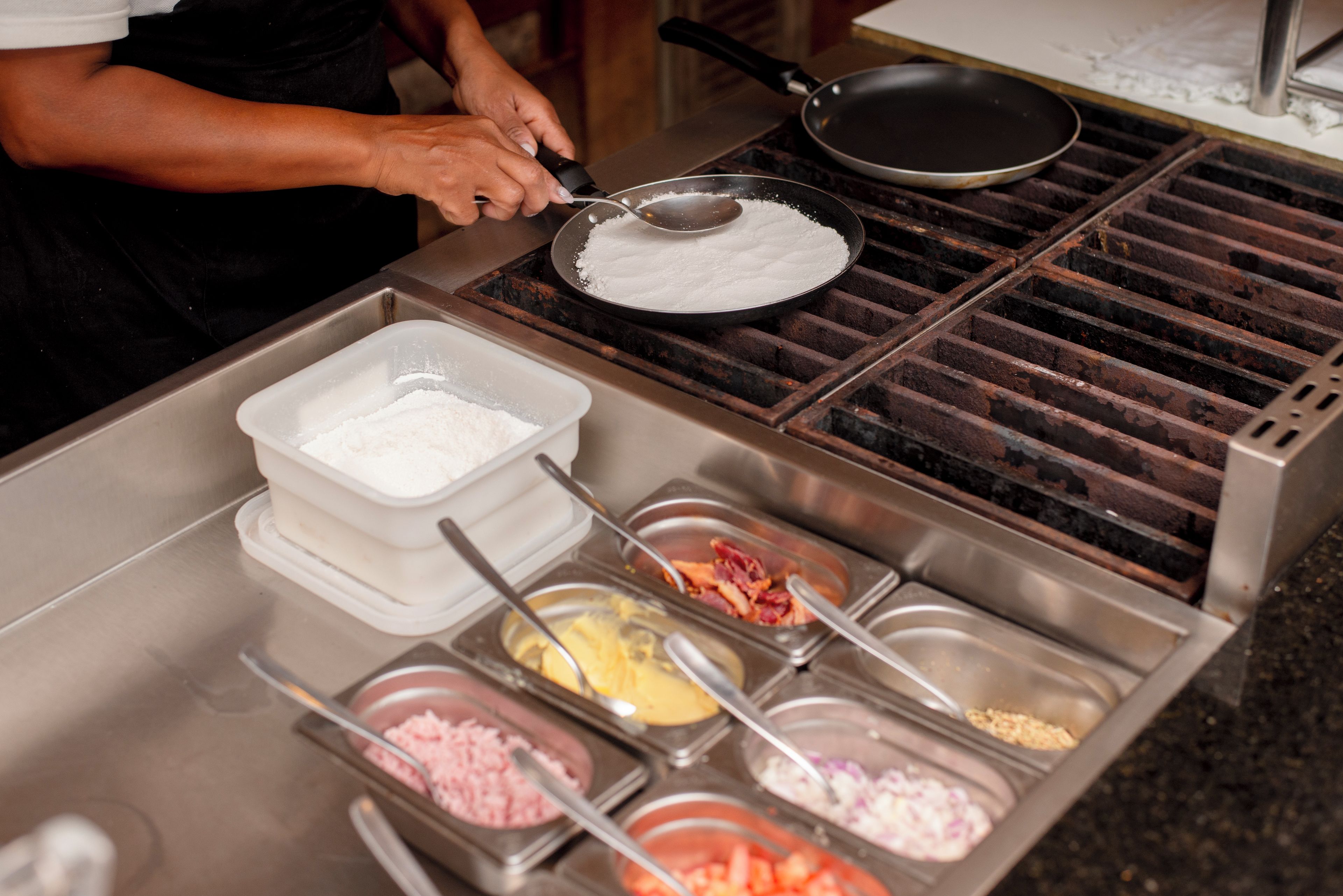 A buffet setup with various food containers and a cooking area.